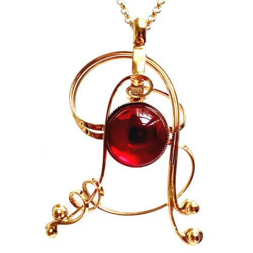 Pendentif doré avec pierre rouge.